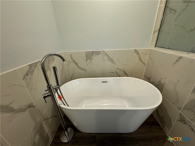 bathroom with a bathing tub and tile walls