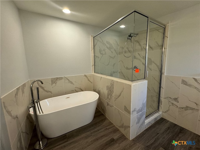 bathroom featuring wood-type flooring, separate shower and tub, and tile walls