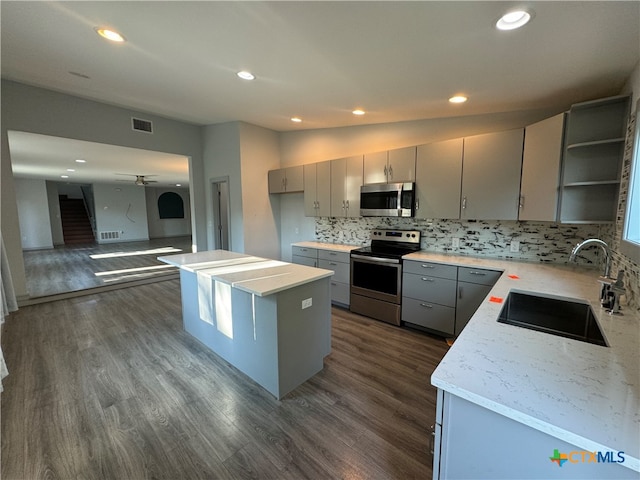 kitchen with dark wood-type flooring, a kitchen island, appliances with stainless steel finishes, and sink