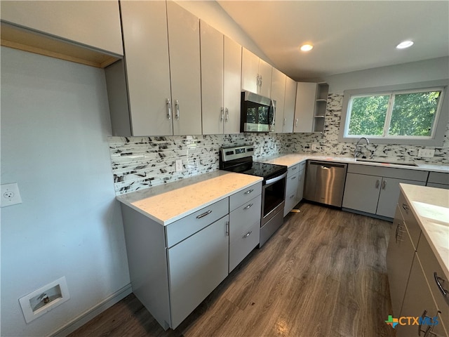 kitchen with dark wood-type flooring, sink, tasteful backsplash, gray cabinets, and appliances with stainless steel finishes