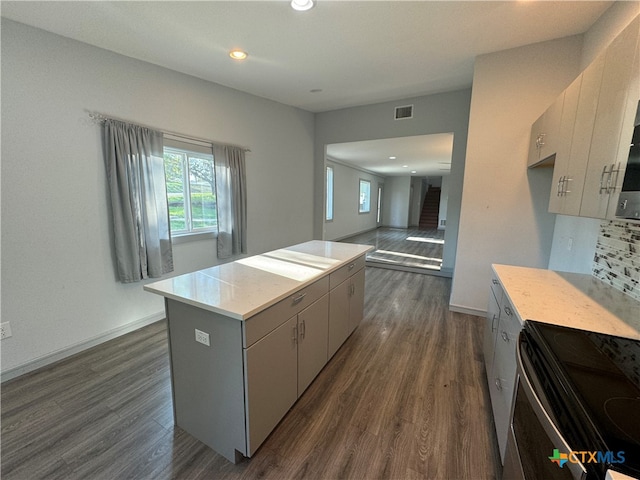 kitchen featuring stainless steel electric range oven, decorative backsplash, dark hardwood / wood-style flooring, and a center island