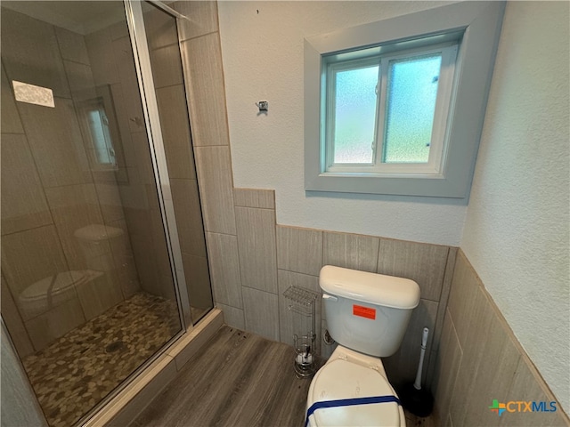 bathroom featuring hardwood / wood-style floors, toilet, and a shower with door