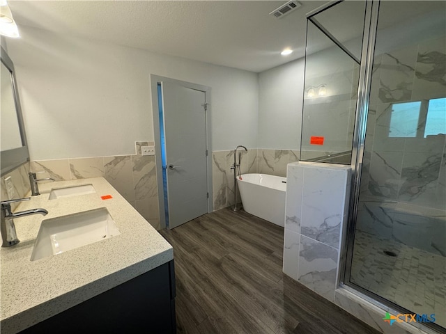 bathroom with tile walls, vanity, hardwood / wood-style flooring, and separate shower and tub