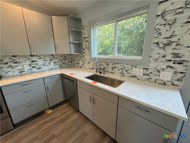 kitchen featuring dark wood-type flooring, dishwasher, sink, gray cabinets, and backsplash