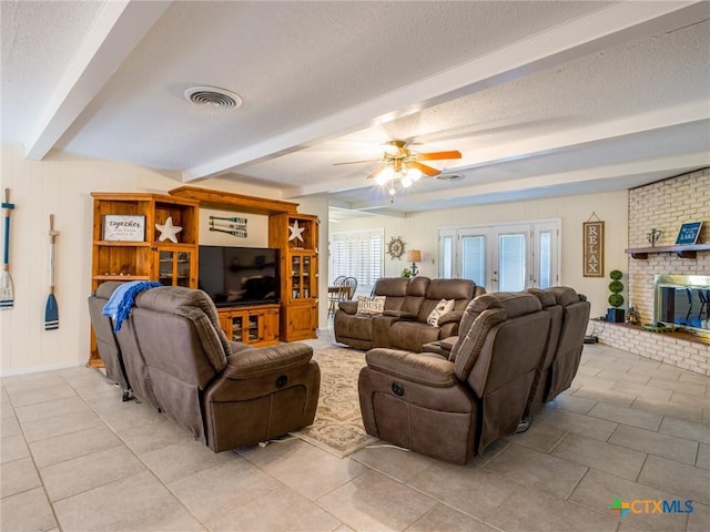 106 Flamingo Cir, Marble Falls, TX 78654 - living room featuring a textured ceiling, light tile patterned flooring, a ceiling fan, beam ceiling, and a fireplace