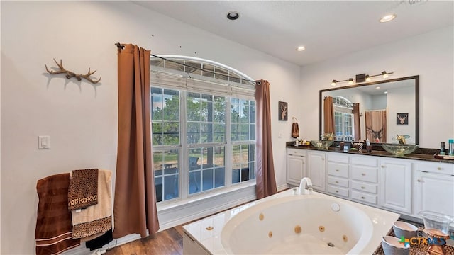 bathroom with vanity, wood-type flooring, and a relaxing tiled tub