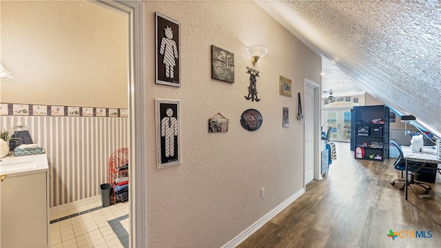 hallway featuring hardwood / wood-style floors, vaulted ceiling, and a textured ceiling