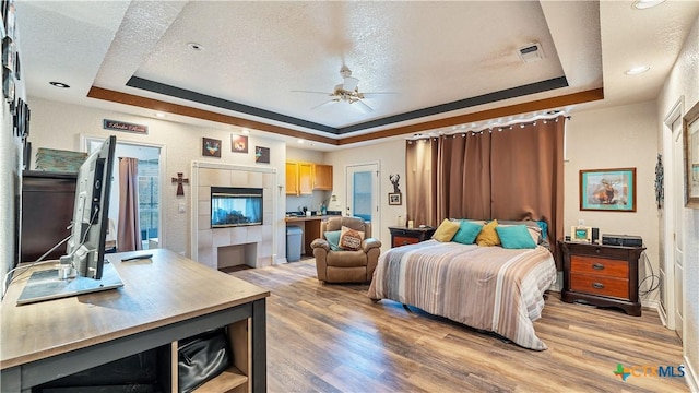 bedroom with wood-type flooring and a raised ceiling