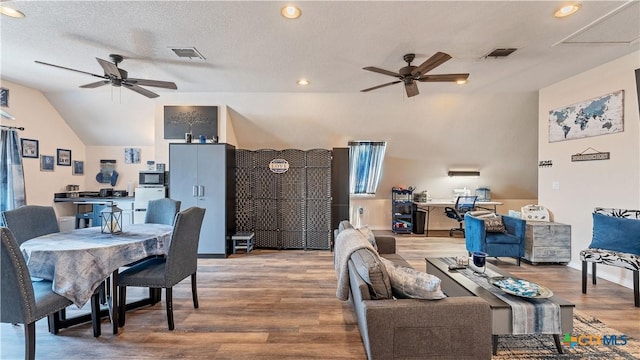 living room with wood-type flooring, vaulted ceiling, a textured ceiling, and ceiling fan