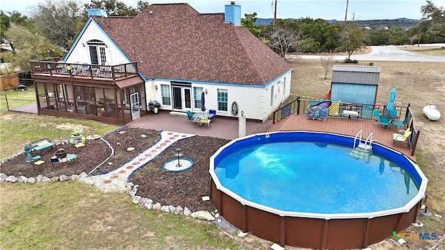 view of pool featuring a sunroom, area for grilling, a yard, and a deck