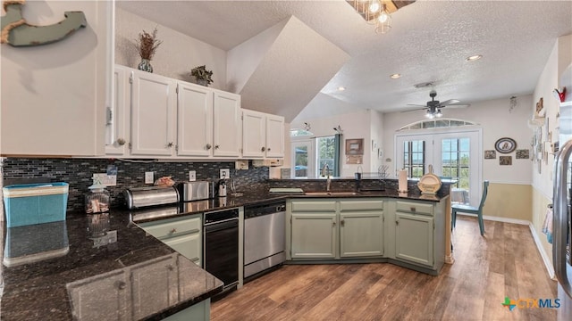 kitchen with sink, dark stone countertops, kitchen peninsula, dishwasher, and white cabinets