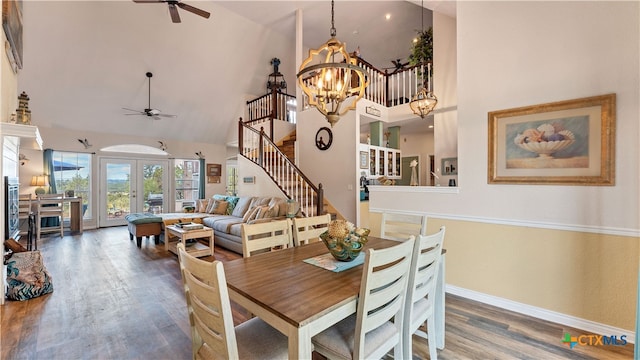 dining area featuring dark hardwood / wood-style floors, ceiling fan with notable chandelier, high vaulted ceiling, and french doors