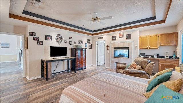 living room featuring wood-type flooring, a raised ceiling, sink, and a textured ceiling