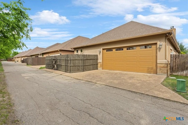 exterior space featuring fence, concrete driveway, stucco siding, and a garage