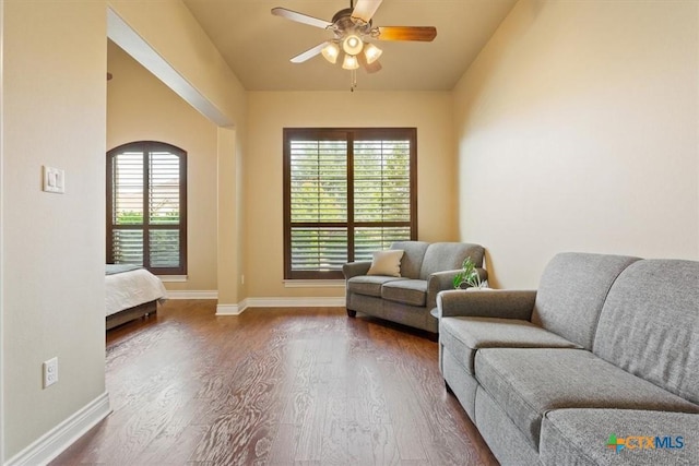 living area with baseboards, dark wood-style floors, and ceiling fan