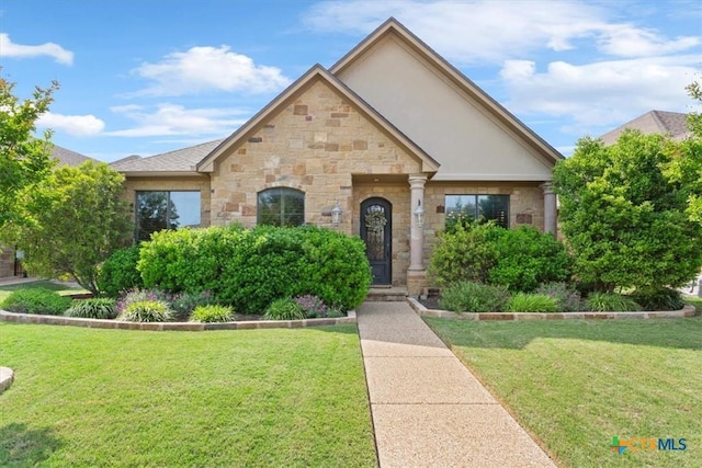 view of front of house with stone siding, a front lawn, and stucco siding