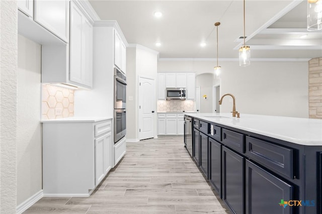 kitchen featuring pendant lighting, sink, crown molding, stainless steel appliances, and white cabinets