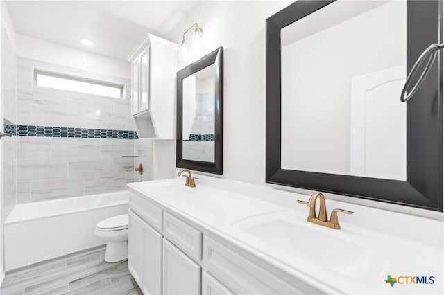 full bathroom featuring vanity, tiled shower / bath, and toilet