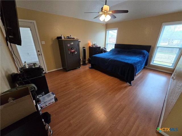 bedroom featuring multiple windows, hardwood / wood-style floors, and ceiling fan