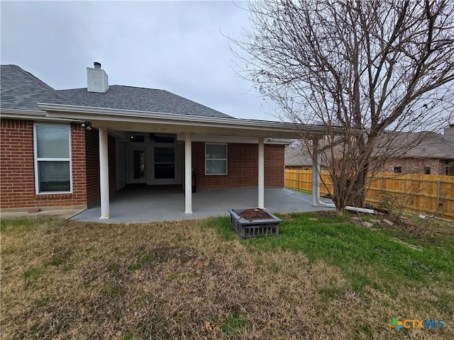 back of house featuring a patio, a lawn, and a fire pit