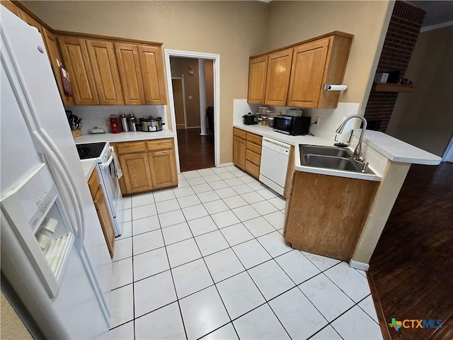 kitchen with tasteful backsplash, white appliances, light tile patterned flooring, and sink