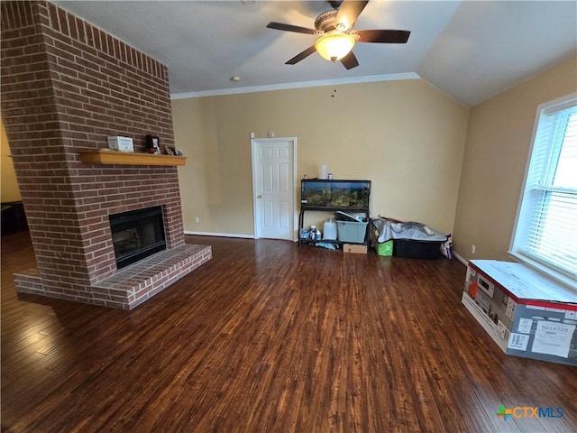 unfurnished living room with crown molding, vaulted ceiling, dark hardwood / wood-style floors, ceiling fan, and a fireplace