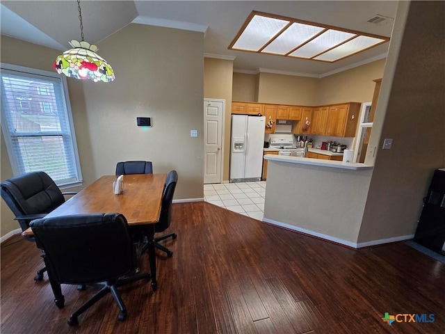 dining area with crown molding, lofted ceiling, and light hardwood / wood-style floors