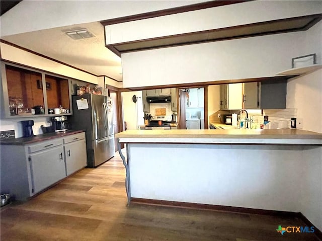 kitchen featuring washer / dryer, sink, light hardwood / wood-style flooring, gray cabinets, and stainless steel appliances