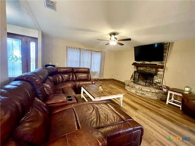 living room with hardwood / wood-style flooring, a fireplace, a textured ceiling, and ceiling fan