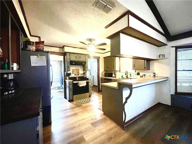 kitchen featuring hardwood / wood-style flooring, appliances with stainless steel finishes, tasteful backsplash, a textured ceiling, and kitchen peninsula