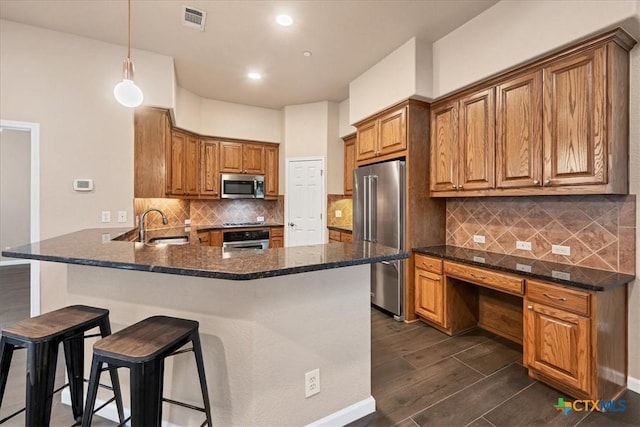 kitchen featuring kitchen peninsula, hanging light fixtures, stainless steel appliances, a kitchen bar, and sink