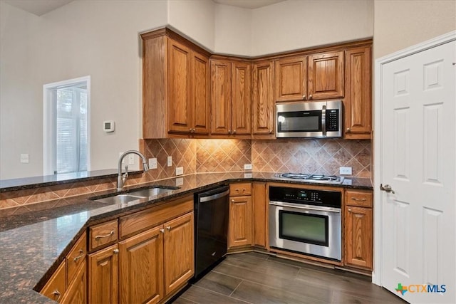 kitchen with stainless steel appliances, dark stone countertops, decorative backsplash, and sink