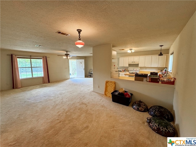 living room with ceiling fan, a textured ceiling, and light carpet