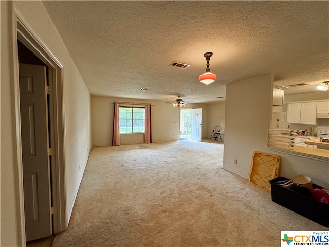 unfurnished living room with a textured ceiling, light colored carpet, and ceiling fan