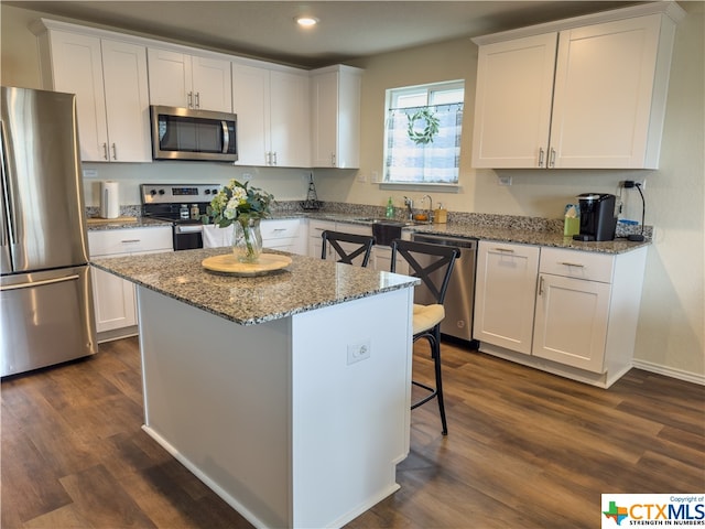 kitchen featuring stainless steel appliances, a kitchen bar, white cabinetry, and a center island