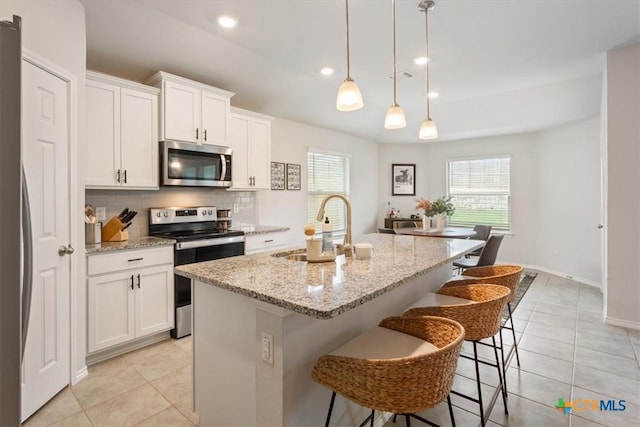 2407 Freddie L Nichols Sr Dr, Harker Heights, TX 76548 - kitchen with appliances with stainless steel finishes, tasteful backsplash, light tile patterned floors, an island with sink, and white cabinets