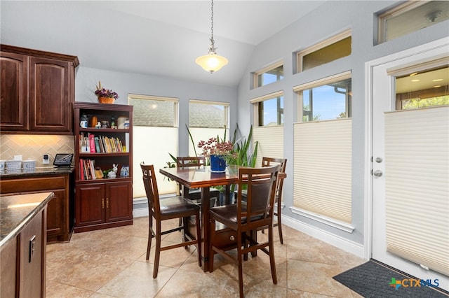 dining space featuring light tile patterned floors and vaulted ceiling