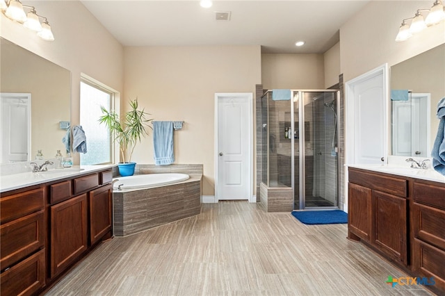 bathroom with wood-type flooring, separate shower and tub, and vanity