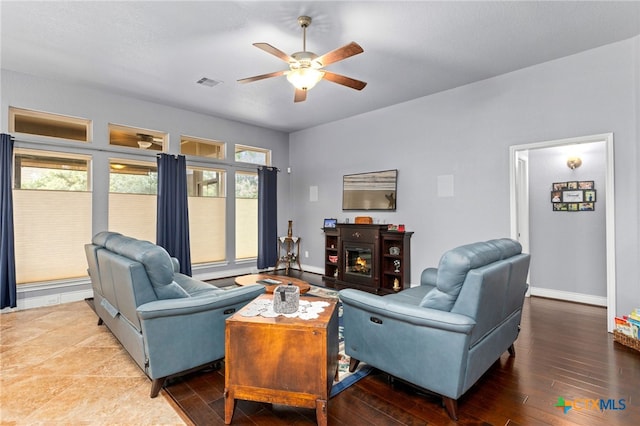 living room with a fireplace, wood-type flooring, and ceiling fan