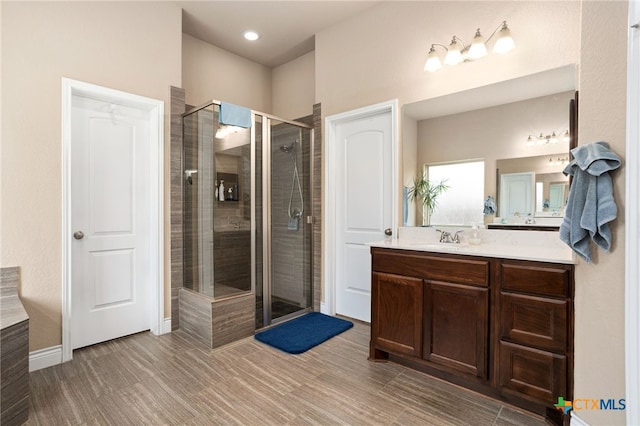 bathroom featuring a shower with shower door and vanity