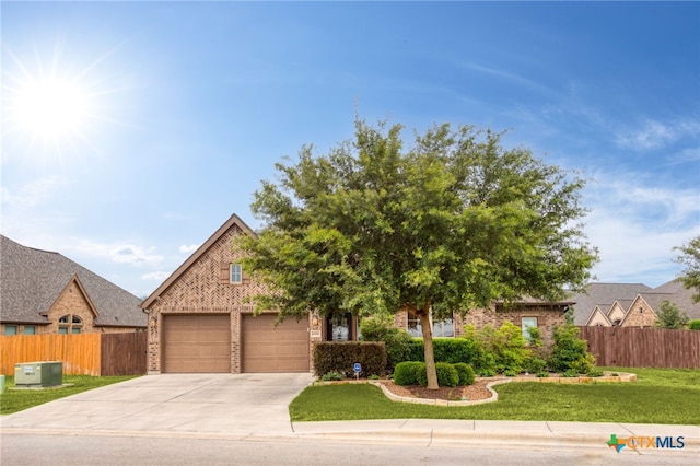 view of front of property with a garage, a front lawn, and central AC