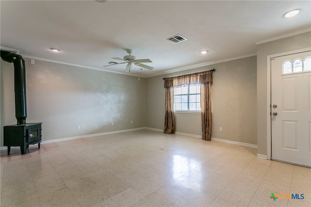 foyer with ceiling fan, a wood stove, and crown molding