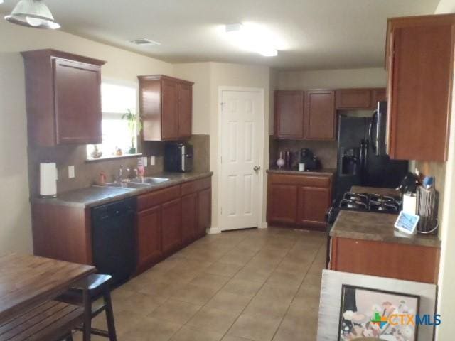 kitchen featuring sink, backsplash, black appliances, and light tile patterned floors