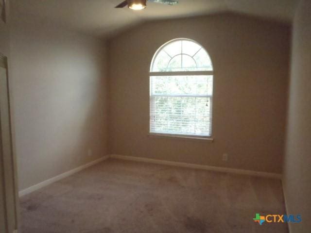 carpeted spare room with ceiling fan and vaulted ceiling