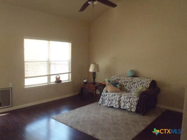 living area with ceiling fan, dark hardwood / wood-style flooring, and lofted ceiling