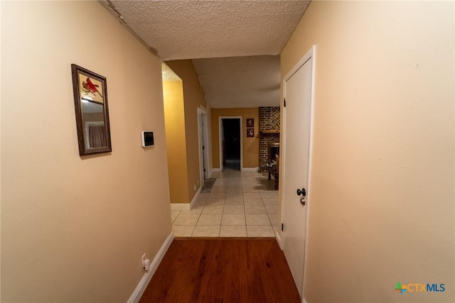 hall with a textured ceiling and light hardwood / wood-style flooring