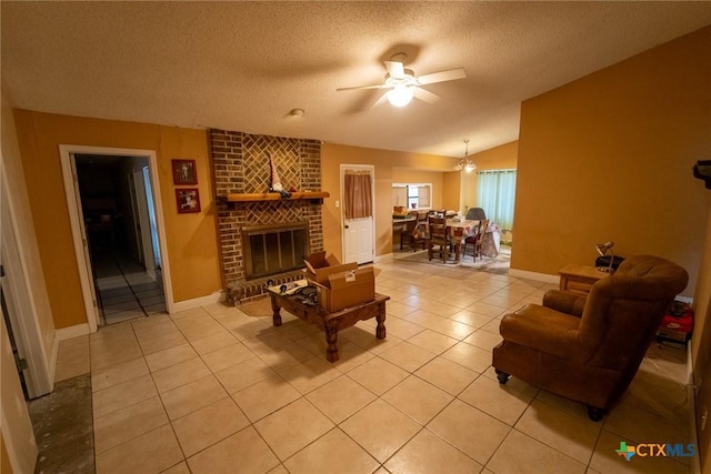 living room featuring lofted ceiling, a brick fireplace, ceiling fan, light tile patterned floors, and a textured ceiling