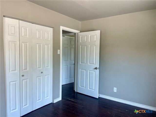 413 Vickers Ave, Seguin, TX 78155 - unfurnished bedroom with baseboards, dark wood-style flooring, and a closet