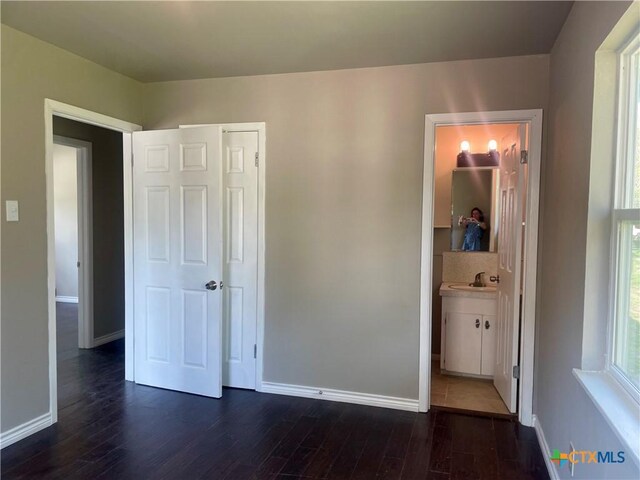 413 Vickers Ave, Seguin, TX 78155 - unfurnished bedroom with dark wood-style floors, baseboards, and a sink