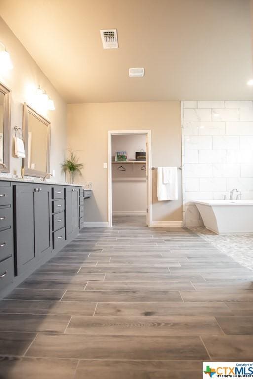 1014 Winchester Dr, Nolanville, TX 76559 - bathroom with wood finish floors, vanity, a soaking tub, baseboards, and backsplash